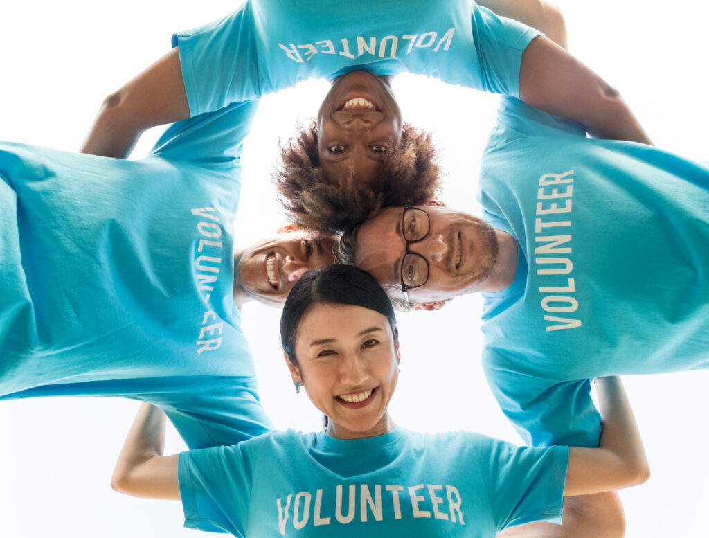 Four volunteers in blue t-shirts smiling in a circle.